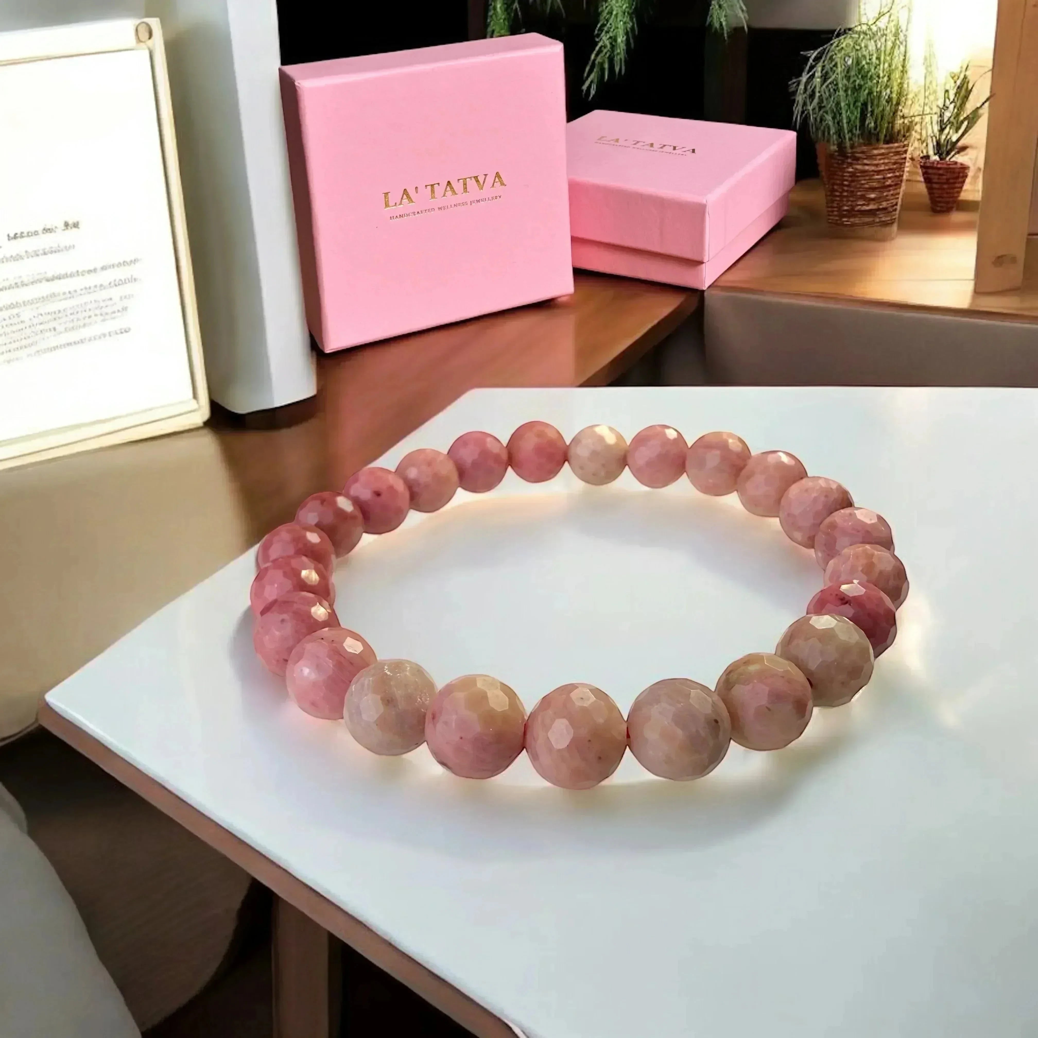 LA TATVA faceted pink Rhodonite gemstone stretch bracelet with marbled patterns, displayed with branded gift boxes.