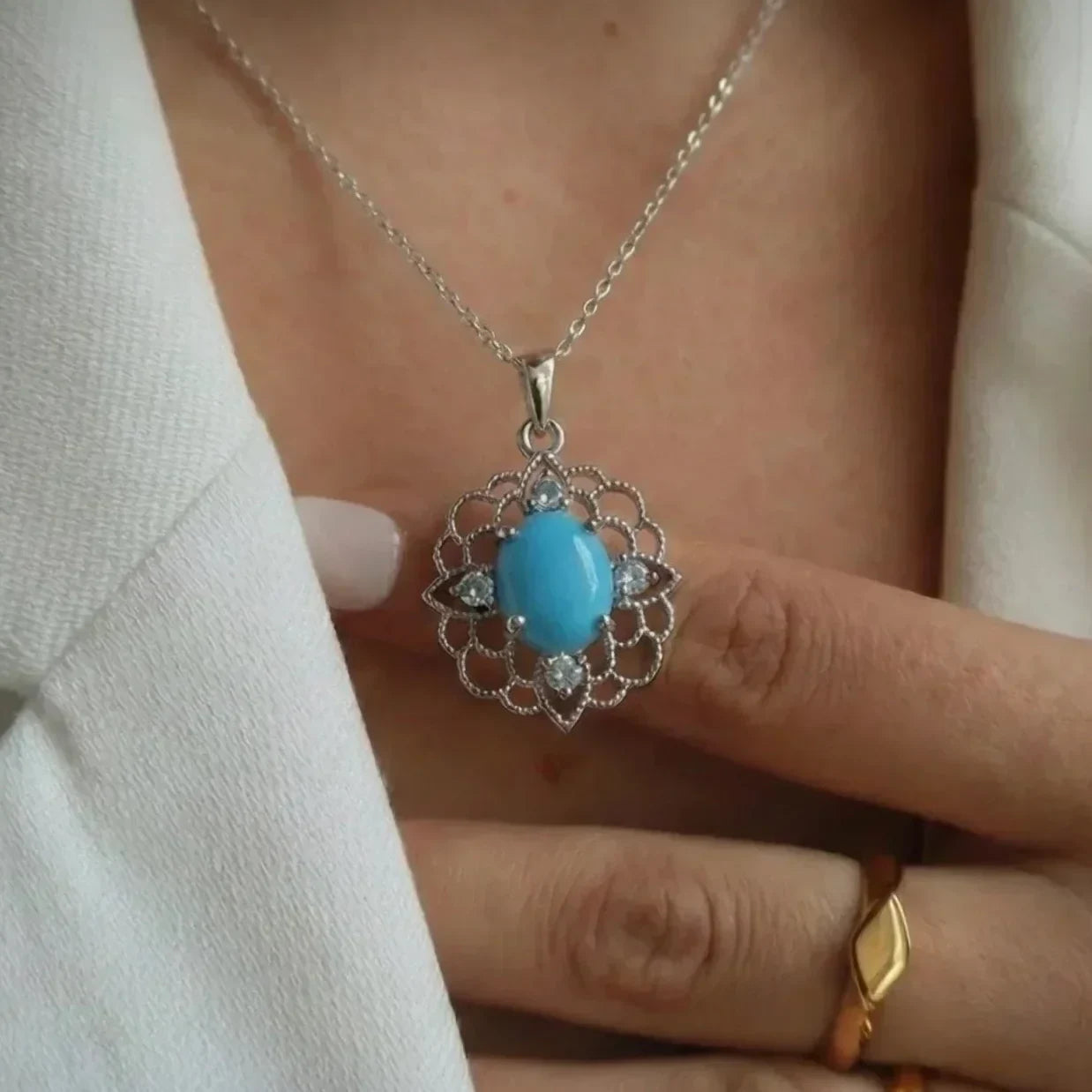 Turquoise pendant necklace on a person wearing a white jacket, with 'Turquoise Elegance' text above.
